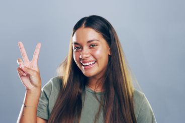Portrait, peace sign and woman in studio, joy and...