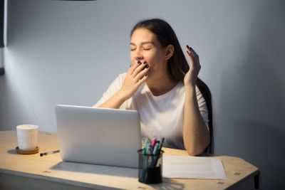Tired sleepy woman yawning at work in home office