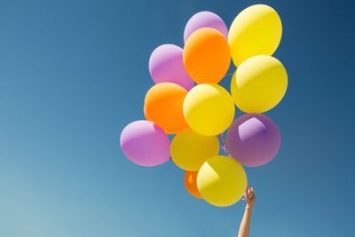 close up of colorful helium balloons in blue sky