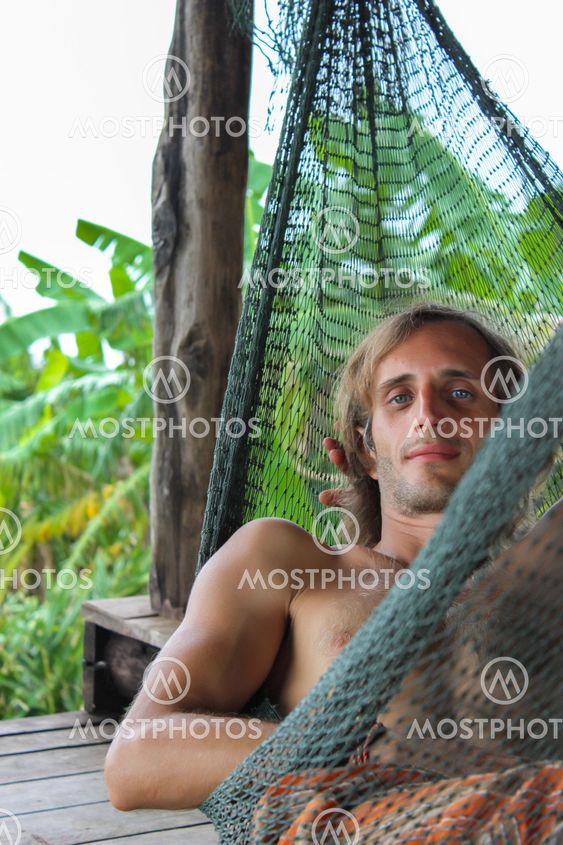 casual happy man relaxing on a hammock in the beach holidays