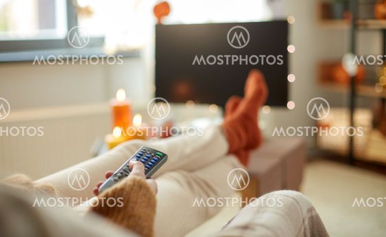 young woman watching tv at home on halloween