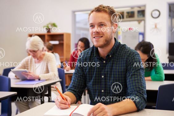 Young man looking up at the board at adult education class
