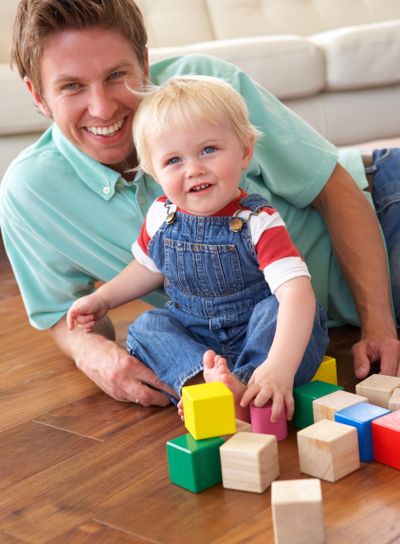 Father And Son Playing With Coloured Blocks At Home