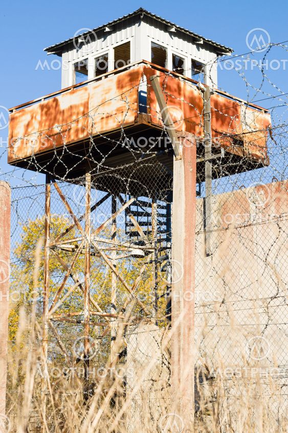 Abandoned watch-tower and prison fence wire barbs