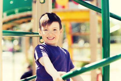 happy little boy climbing on children playground