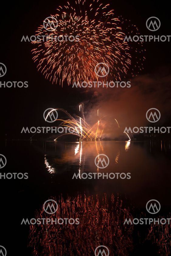 Colorful fireworks on the black sky background and water reflections