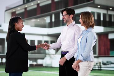 Professional real estate agent shakes hands in front