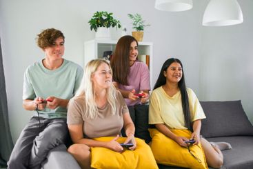 Cheerful group of friends playing video games together...