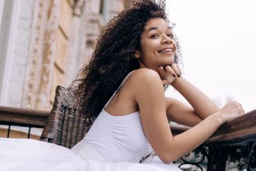 A young African woman in an elegant white dress and...