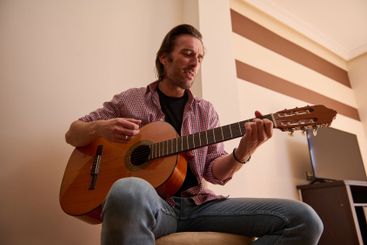 Man playing acoustic guitar in a cozy indoors setting...