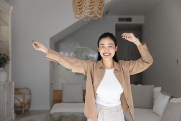 Cheerful beautiful 20s Asian girl dancing at new home