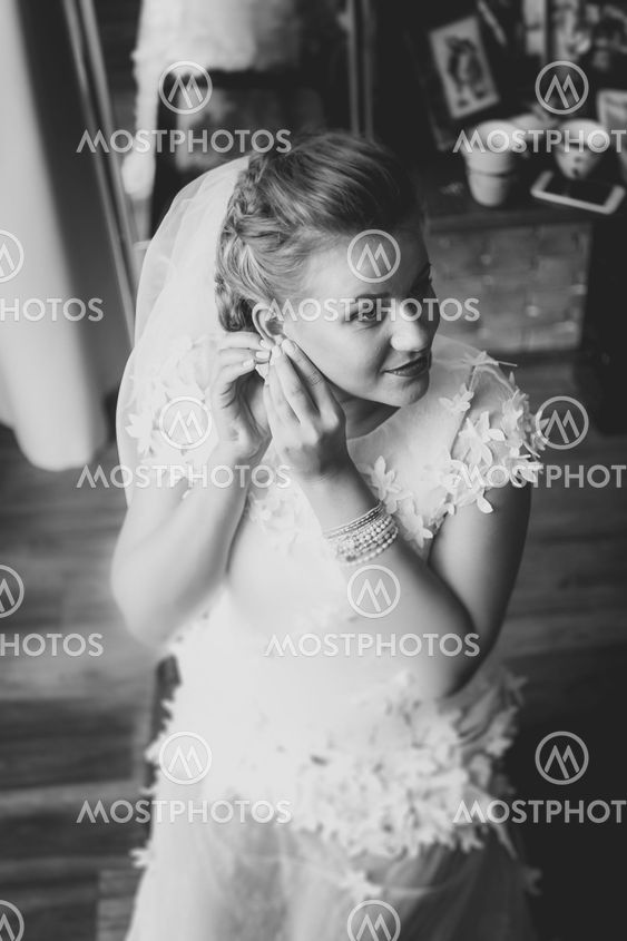Black and white portrait of gorgeous bride putting on...