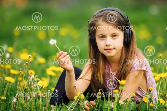 Cute little girl in headphones enjoying music in nature.