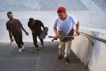 Friends, skateboard group and steps in city, street or...