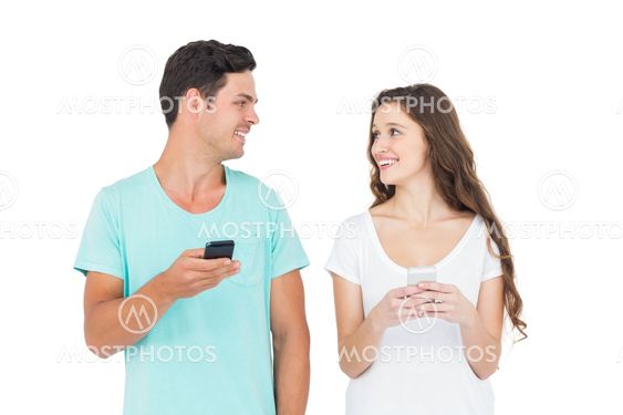 Smiling couple using their smartphones