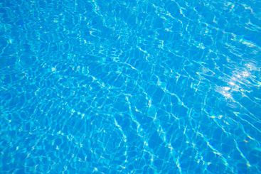 Bright sunlight illuminating clear blue water in a...