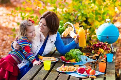 Mother and daughter set table for picnic in autumn