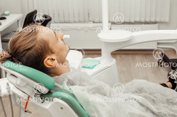 A young and satisfied male patient in the dentist's...