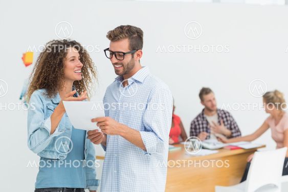 Happy designers looking at digital tablet together and chatting