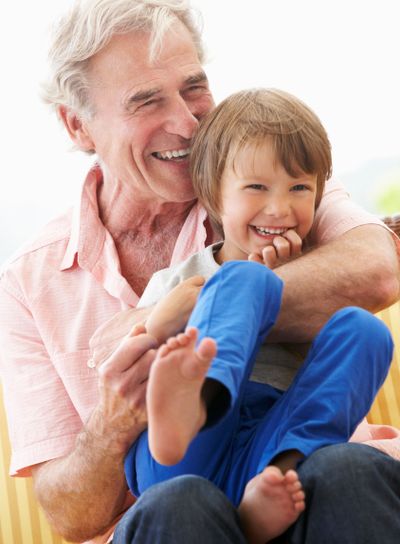 Grandfather Cuddling Grandson On Garden Seat