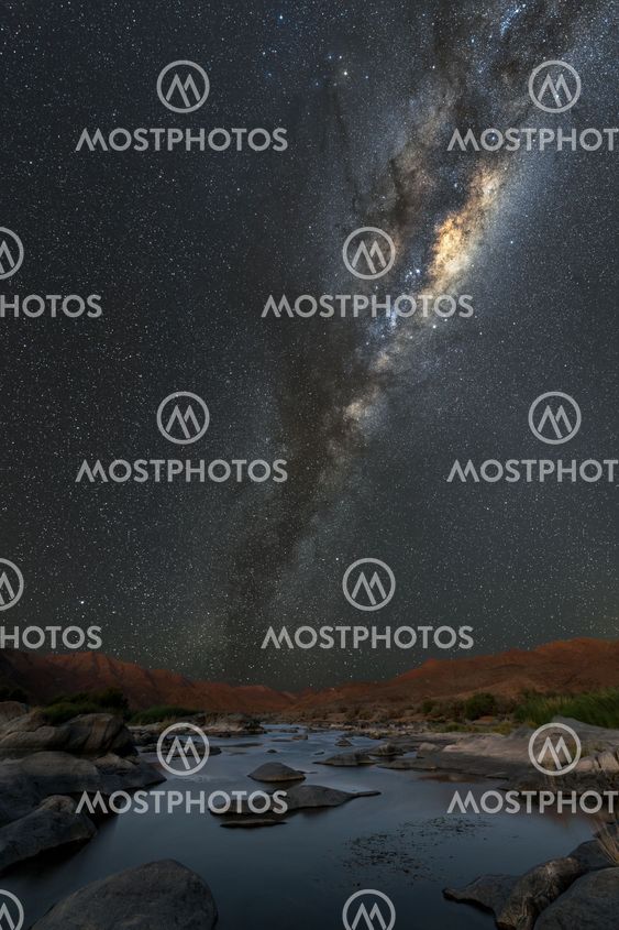 A vertical night sky landscape with the Milky Way and a...