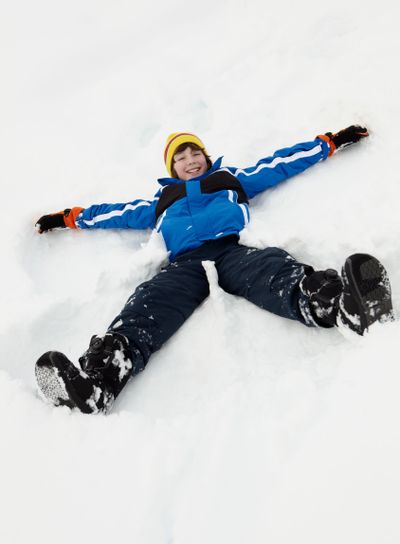 Young Boy Making Snow Angel On Slope