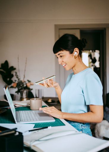 Smiling young female freelancer talking through speaker...