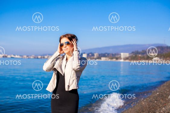 Beautiful young woman walking on the beach in winter sunny day alone