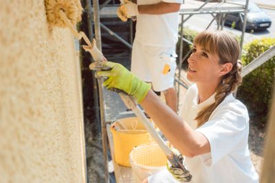 Woman painter painting a wall with yellow paint