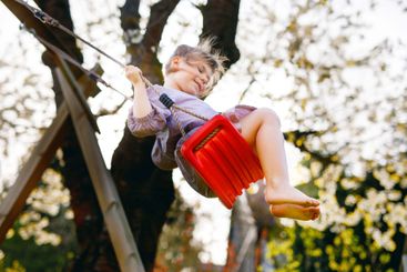 Happy little toddler girl having fun on swing in...