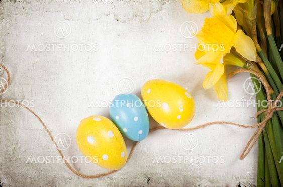 Easter background with painted eggs and blooming daffodils
