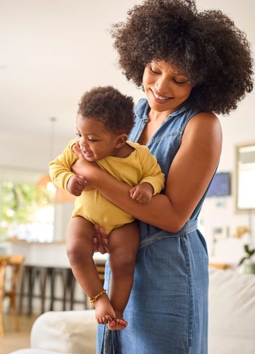 Loving Mother Indoors At Home Standing Cuddling Baby...