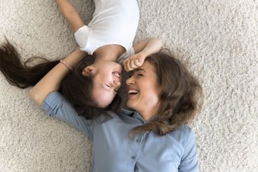 Affectionate young mom little daughter lying playing on...