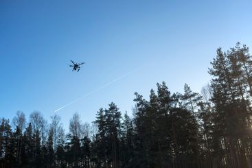drone flying in the blue sky above the trees
