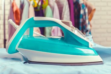 Iron on ironing board on light home interior background