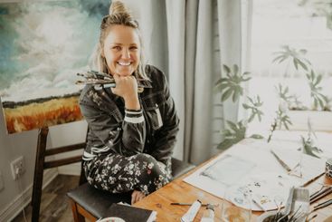 Paintbrush, painting and portrait of woman in studio at...