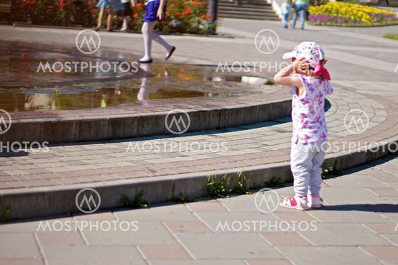 Baby near a splashing fontain in the center of town 12...