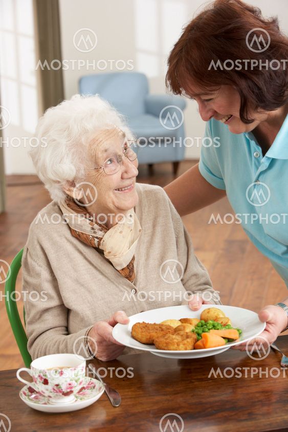 Senior Woman Being Served Meal By Carer