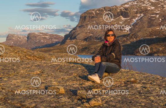Woman sitting on rock in sunset