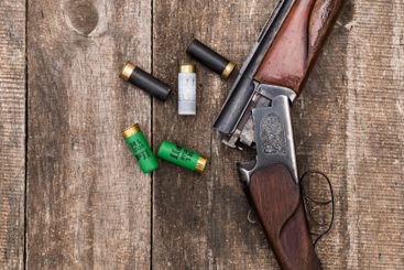 Vintage shotgun and ammunition resting on wood surface...