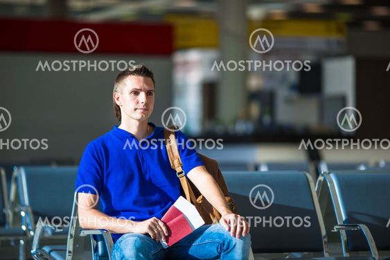 Young man holding passports and boarding pass at airport