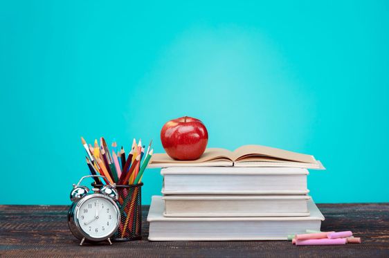 Back to School concept. Books, colored pencils and clock