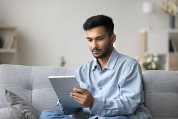 Focused young male freelancer working from home using...