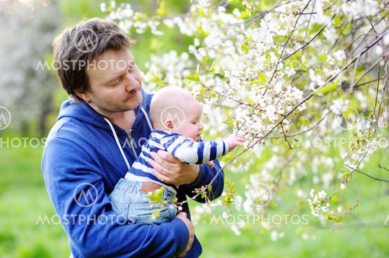 Little baby with father in the blossom garden
