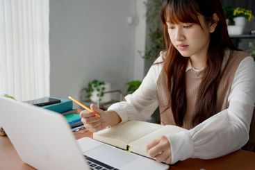 Asian woman using laptop to study student engaged in...