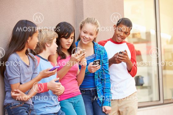 Group Of Children Sitting In Mall Using Mobile Phones