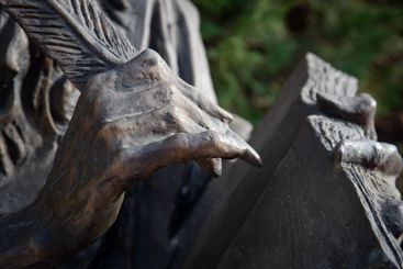 Bronze sculpture of hands holding a feather pen and...