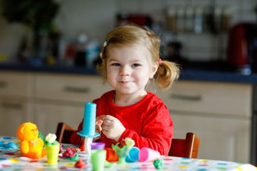 Adorable cute little toddler girl with colorful clay....