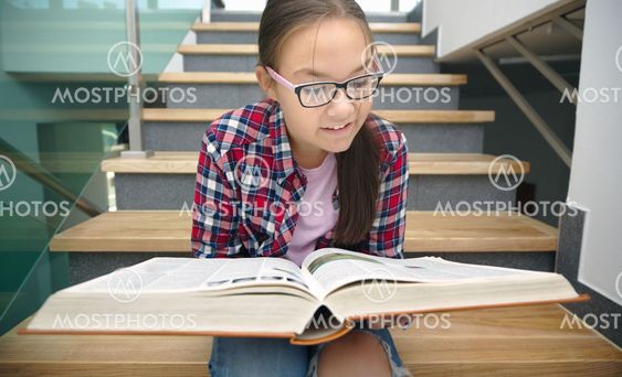 Girl is reading book while sitting on stairs