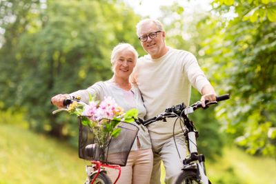 happy senior couple with bicycles at summer park
